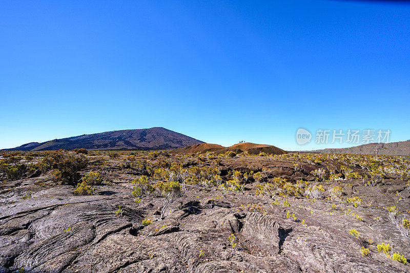 在自然火山景观中，游客们站在山顶下现存火山口凝固的熔岩场中间的小火山口上。Formica Leo, Piton de la Fournaise，留尼旺岛，法国，欧洲。